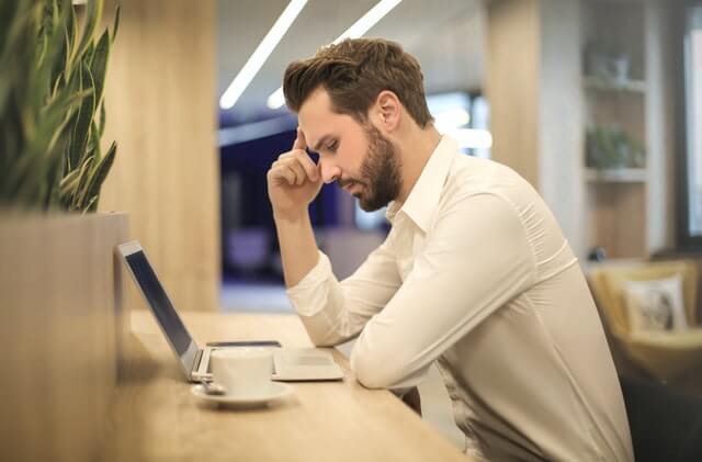 man beside laptop thinking